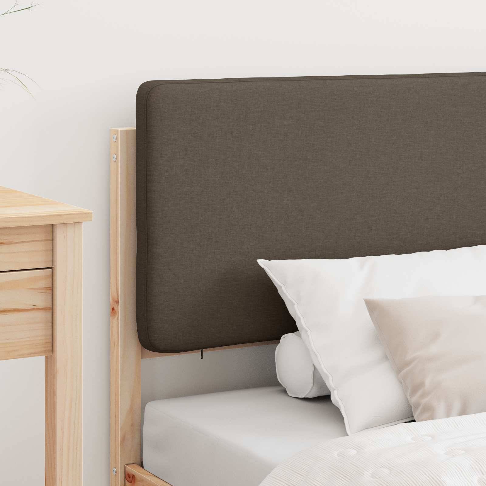 Ein Holzbett mit einer dunkelbraunen gepolsterten Kopfstütze, weißem Kissen und beiger Decke, neben einem Holznachttisch.