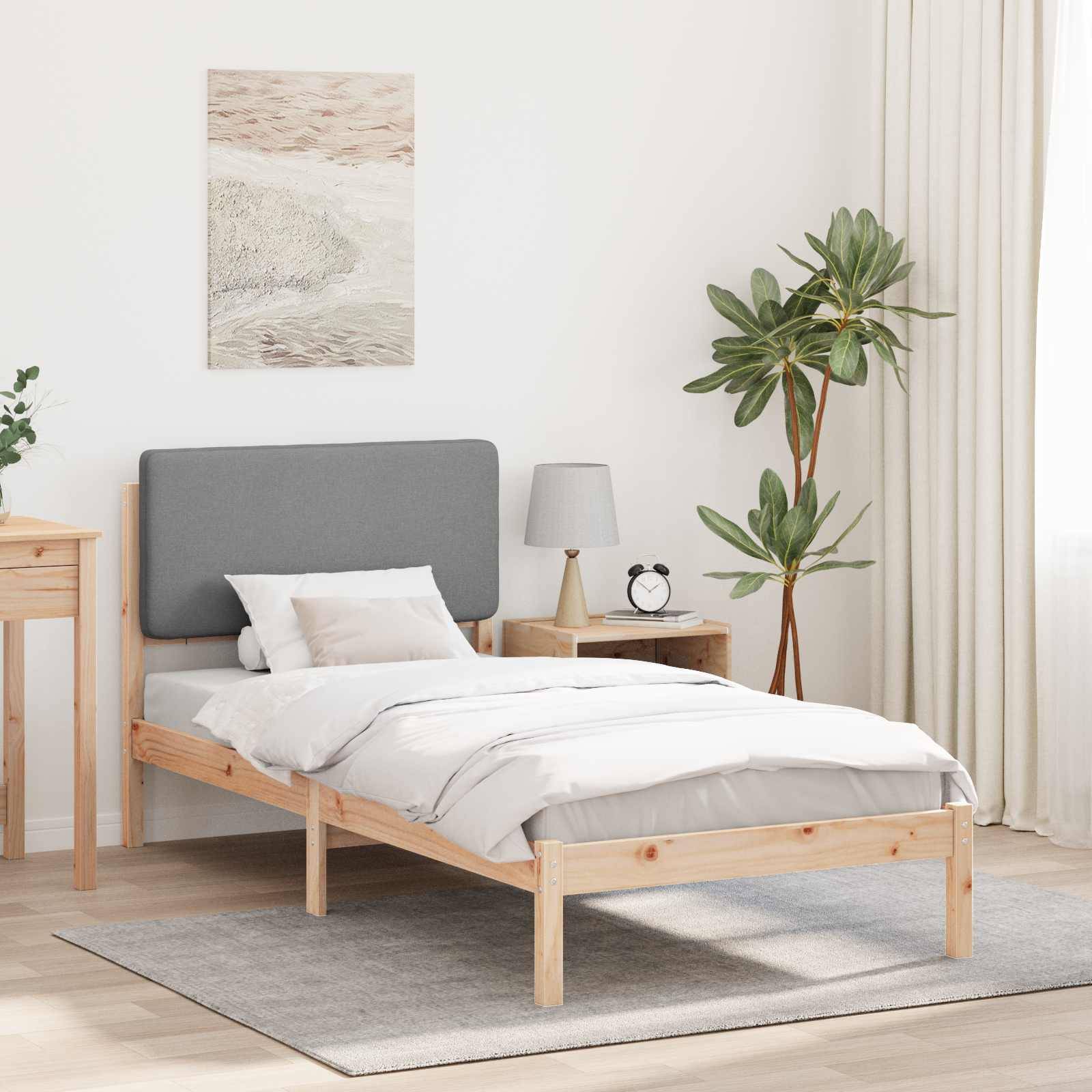 Ein minimalistisches Schlafzimmer zeigt ein Holzbett mit grauer Bettwäsche, einen Nachttisch mit einer Lampe, einer Pflanze und einem maritime-thematischen Gemälde.