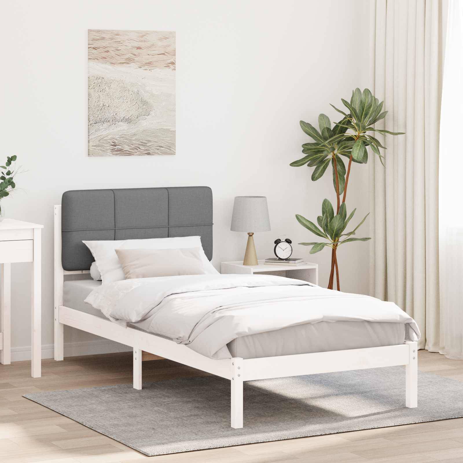 Ein minimalistisches Schlafzimmer mit einem weißen Bett und grauem Kopfteil, weißen Nachttischen und einer Topfpflanze am Fenster. Helle Dekorationsakzente.