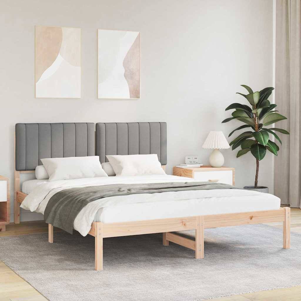 Modernes Schlafzimmer mit einem Holzbett, grauem gepolstertem Kopfteil, zwei abstrakten Wandbildern, einem Nachttisch und einer Pflanze. Weiches Licht.
