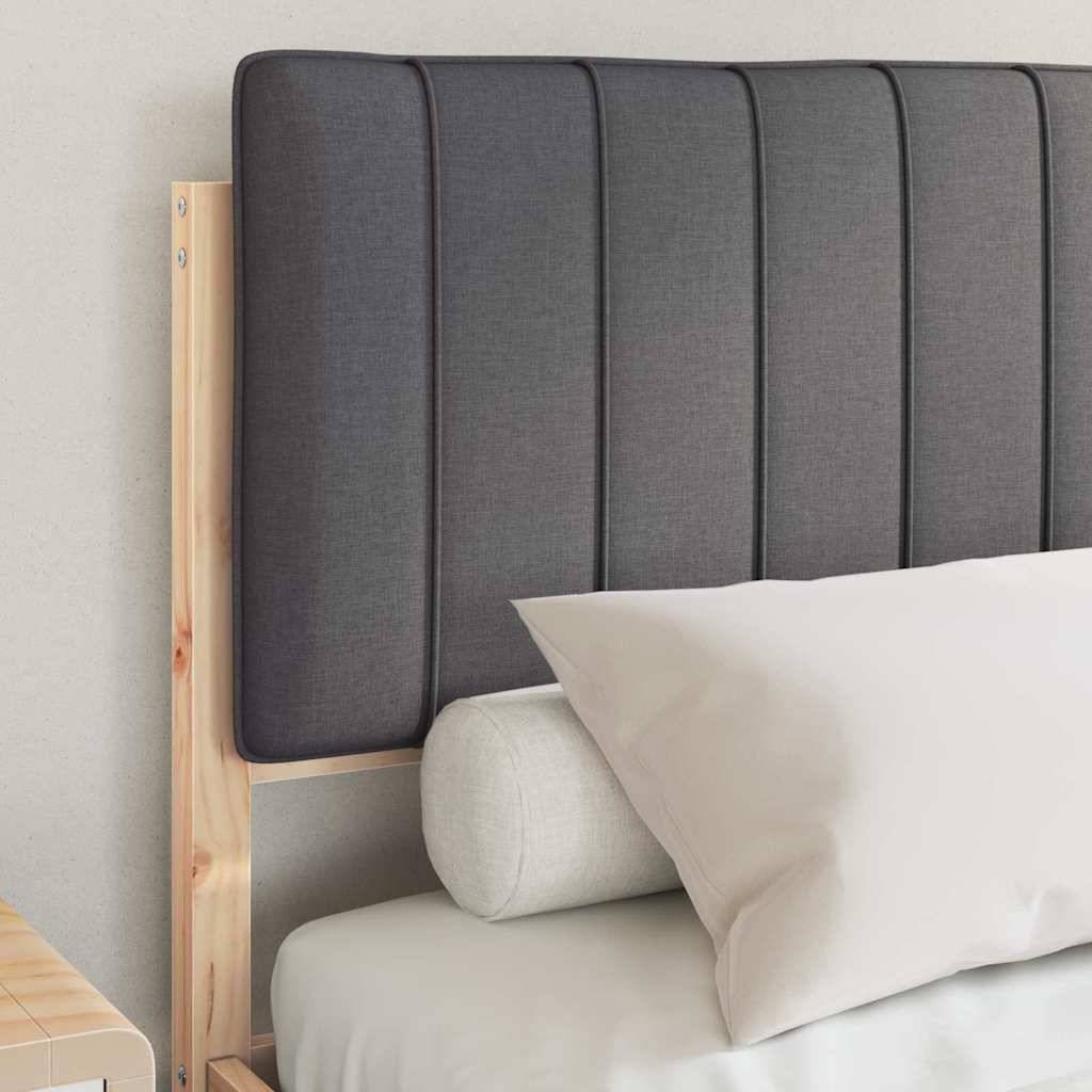 Ein ordentlich gemachtes Bett mit Holzrahmen und hohem, dunkel gepolstertem Kopfteil, ausgestattet mit weißer Bettwäsche und weißem Kissen vor einer hellen Wand.