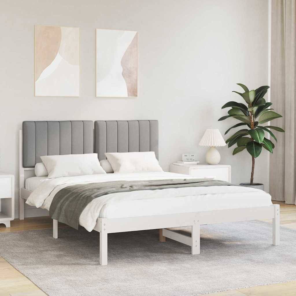 Ein modernes Schlafzimmer mit einem grauen gepolsterten Kopfteil, weißer Bettwäsche und einer beigen Decke. Zwei abstrakte Kunstwerke und eine Topfpflanze ergänzen die Dekoration.