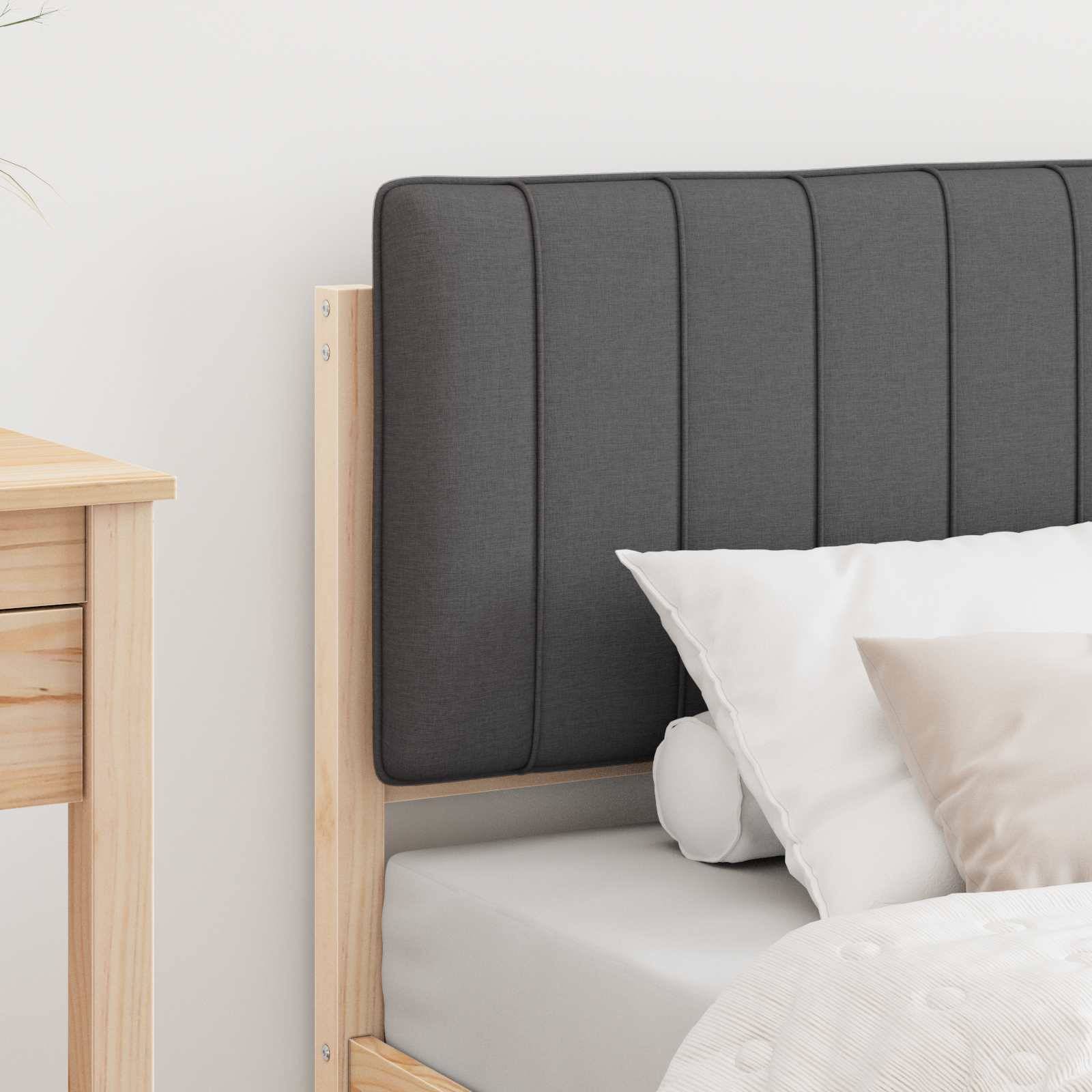 Ein ordentlich gemachtes Bett mit einem Holzrahmen und einem gepolsterten, dunkelgrauen Kopfteil. Weiße Kissen und eine weiße Steppdecke sind auf dem Bett arrangiert.