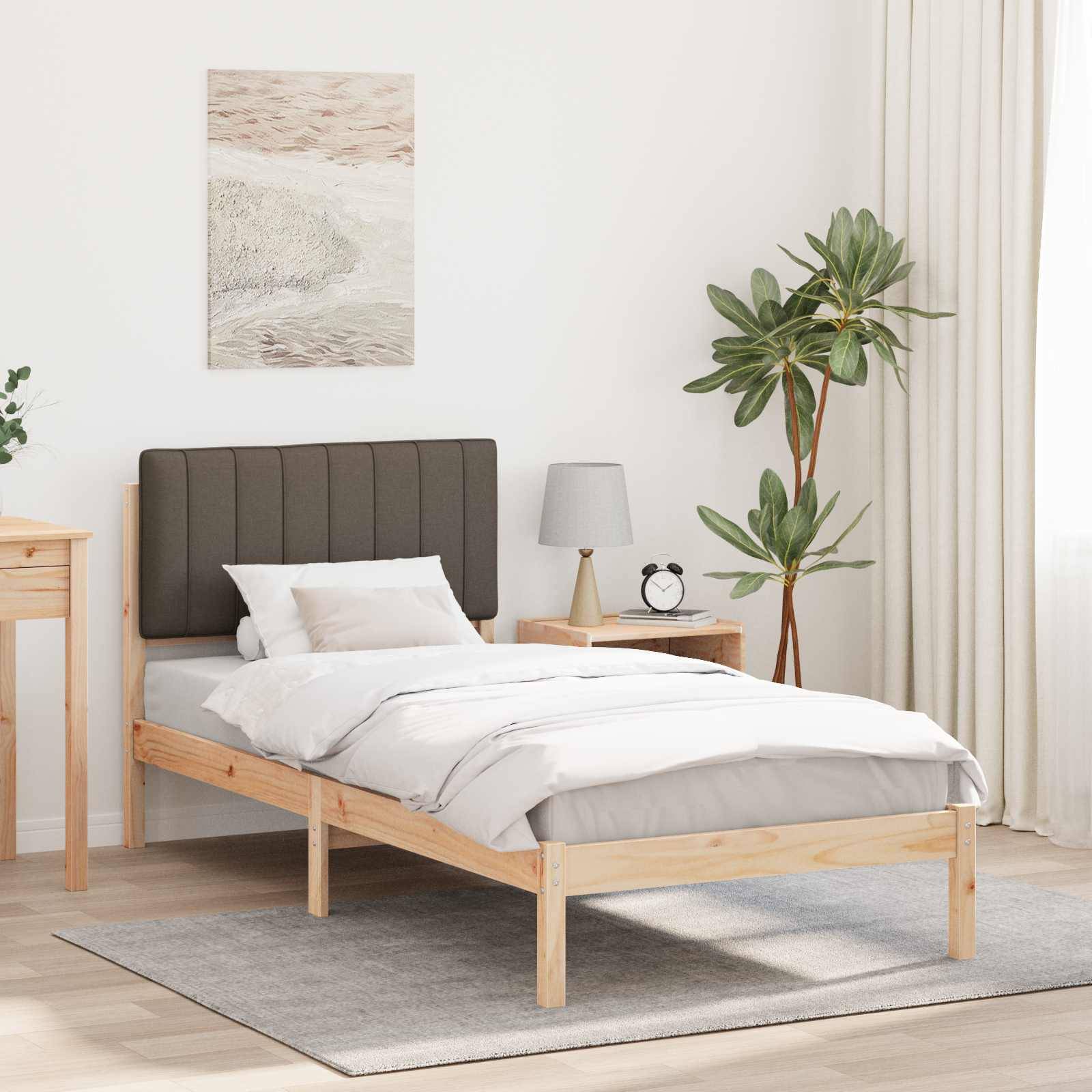 Ein minimalistisches Schlafzimmer mit einem Holzbett, grauem Kopfteil, weißer Bettwäsche, einem Nachttisch mit Lampe und einer Topfpflanze neben den Vorhängen.