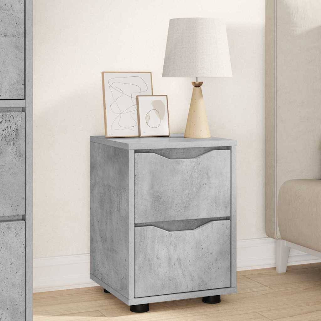 Ein Nachttisch im Betonlook mit zwei Schubladen, auf dem eine Tischlampe und zwei abstrakte gerahmte Kunstwerke stehen, platziert neben einem beigen Sofa.