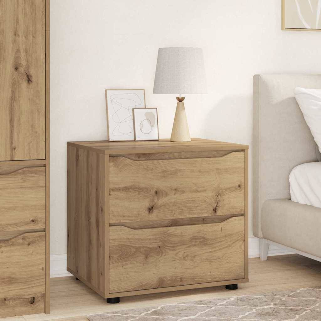 Ein Holznachttisch mit zwei Schubladen, einem beigen Lampenschirm und gerahmter Kunst obenauf, neben einem Stuhl mit einem weißen Kissen in einem gemütlichen Raum.