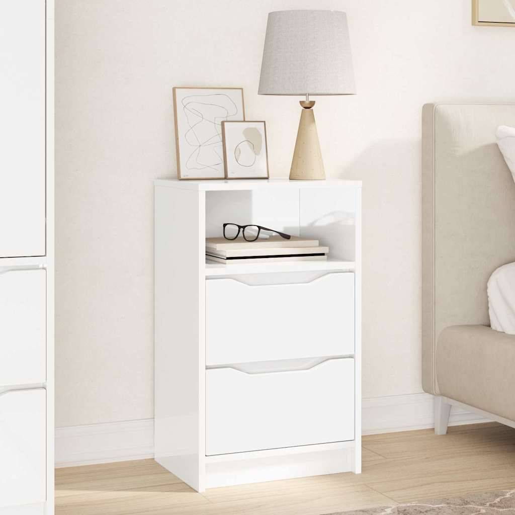 Ein weißer Nachttisch mit zwei Schubladen und einem offenen Regal, auf dem eine Lampe, zwei gerahmte abstrakte Kunstwerke und ein Buch stehen. Rechts davon befindet sich ein beiger Sofa.