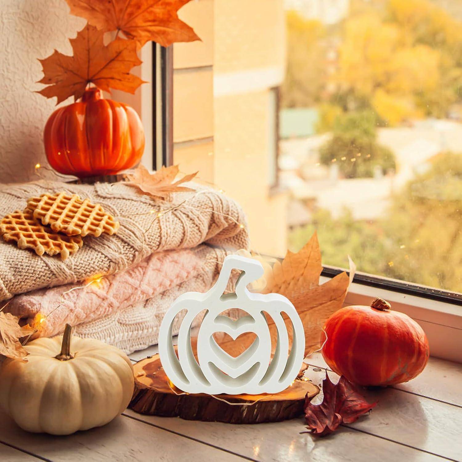 Eine gemütliche Herbstszene am Fenster mit gestapelten Decken, Waffeln, dekorativen Kürbissen und warmem Licht, die ein Gefühl von Herbstwärme hervorruft.