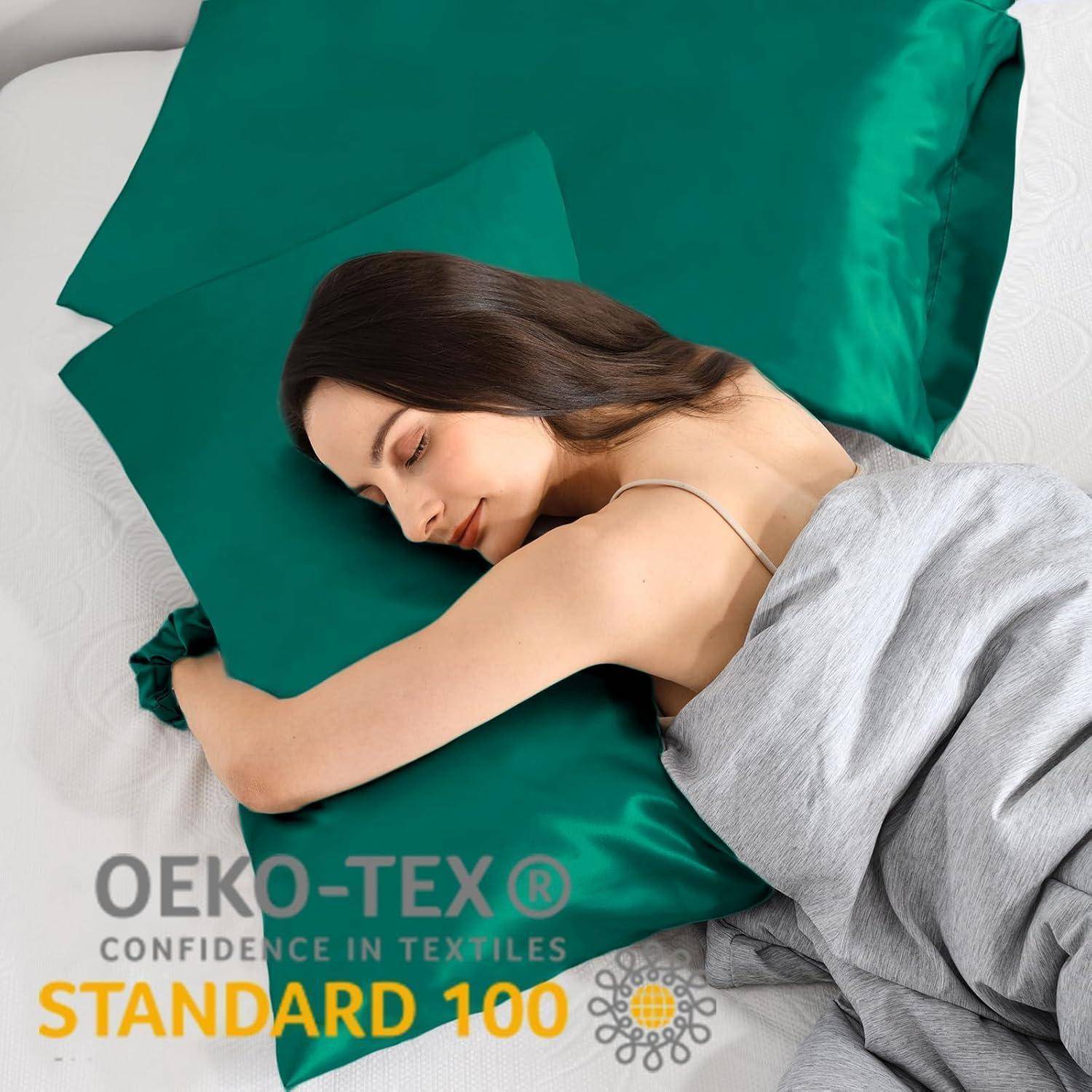Eine Person, die friedlich auf einem smaragdgrünen Kissen und einer Decke schläft. Der Text 'OEKO-TEX KONFIDENZ IN TEXTILIEN STANDARD 100' ist sichtbar.