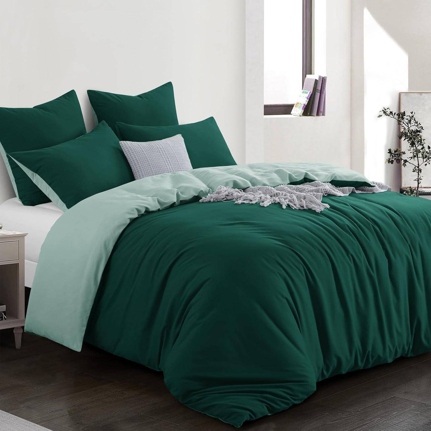 Ein ordentlich gemachtes Bett mit dunkelgrüner Bettwäsche, hellgrünen Laken und mehreren Kissen in einem modernen Schlafzimmer. Ein großes Fenster lässt natürliches Licht herein.