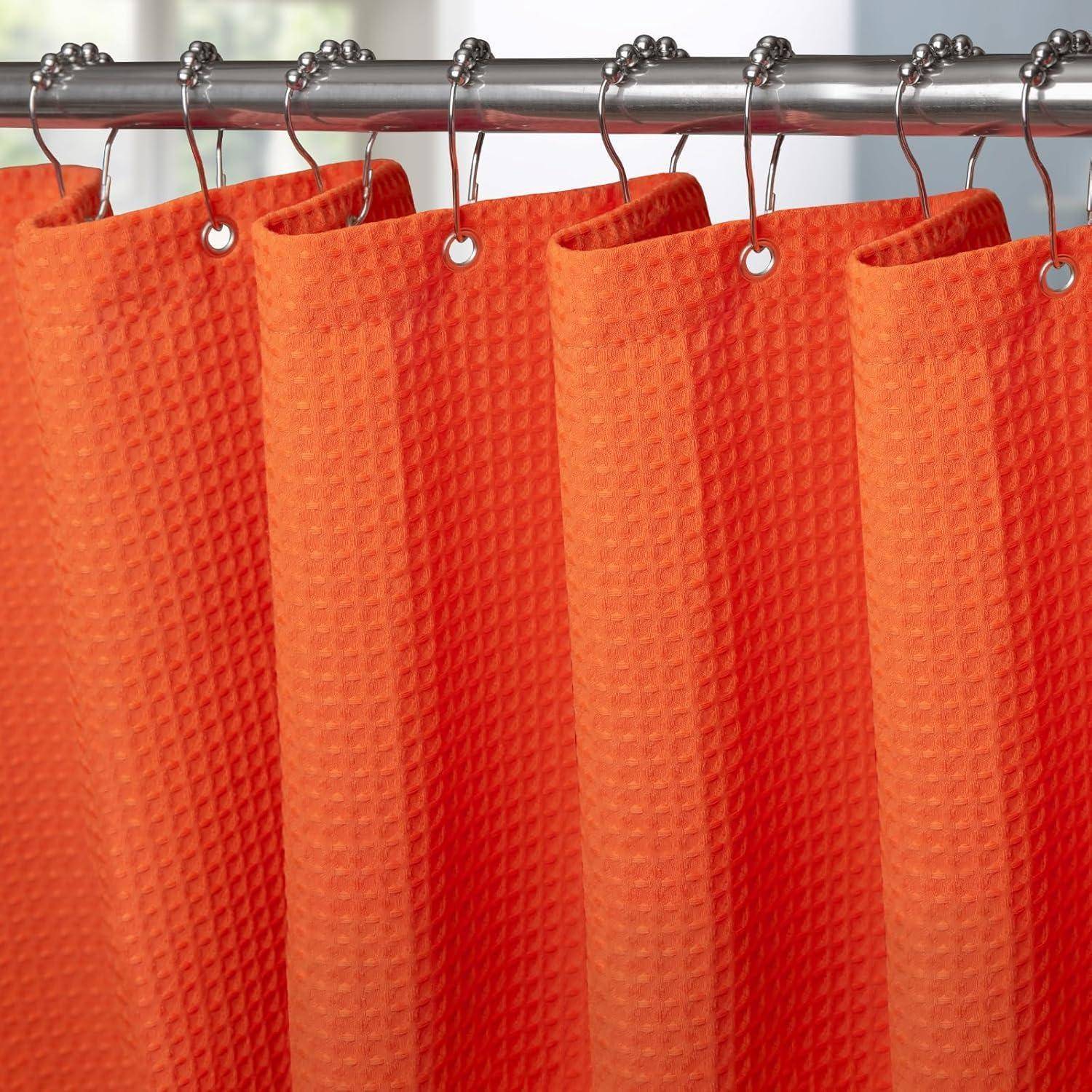 Orangefarbener Duschvorhang mit einem strukturierten Muster hängt an einer Metallstange und unterstreicht seine leuchtende Farbe und Stoffdetails.