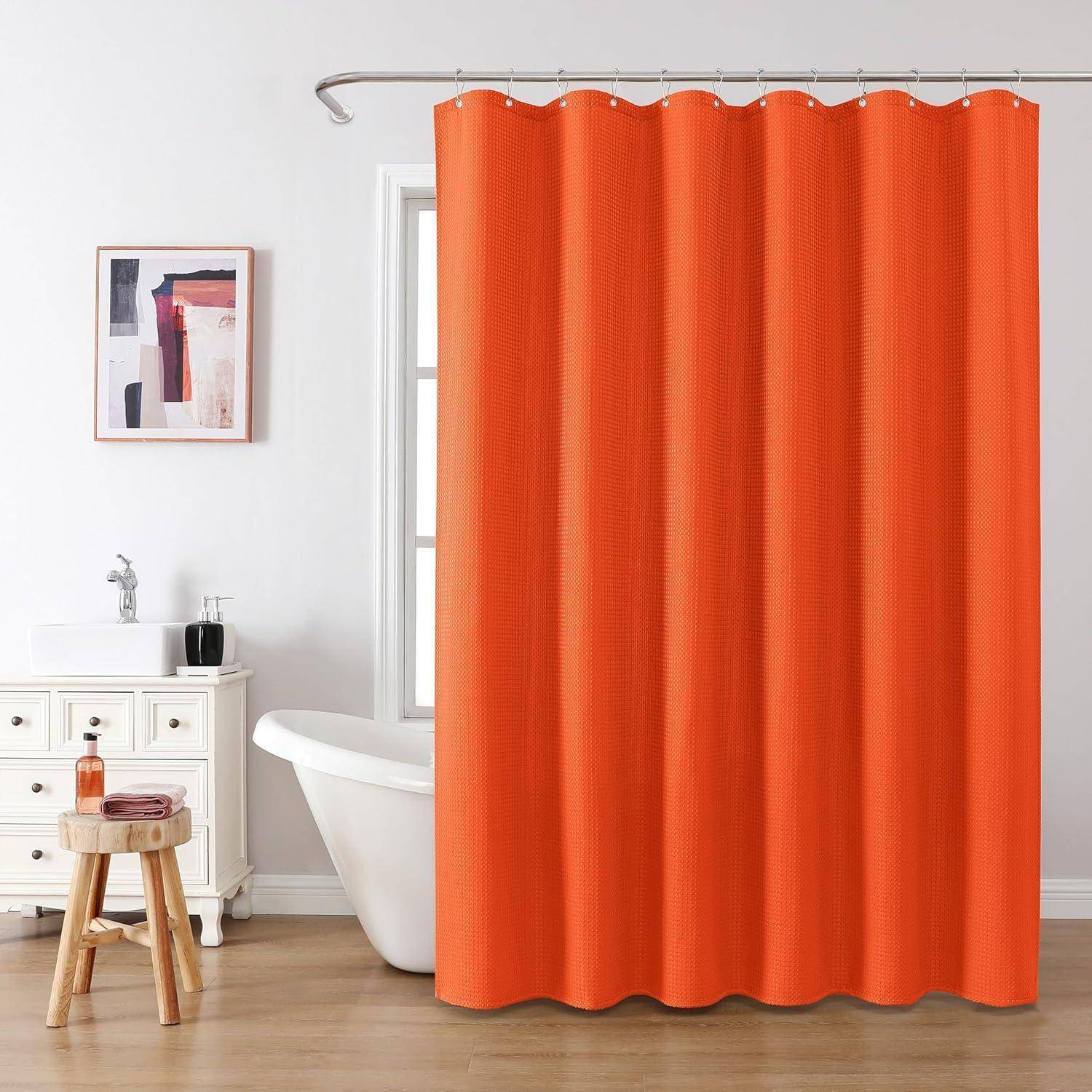 Orangefarbener Duschvorhang in einem Badezimmer mit einer freistehenden Badewanne und einem weißen Waschbecken auf einem Holzboden; ein kleiner Hocker trägt Toilettenartikel.