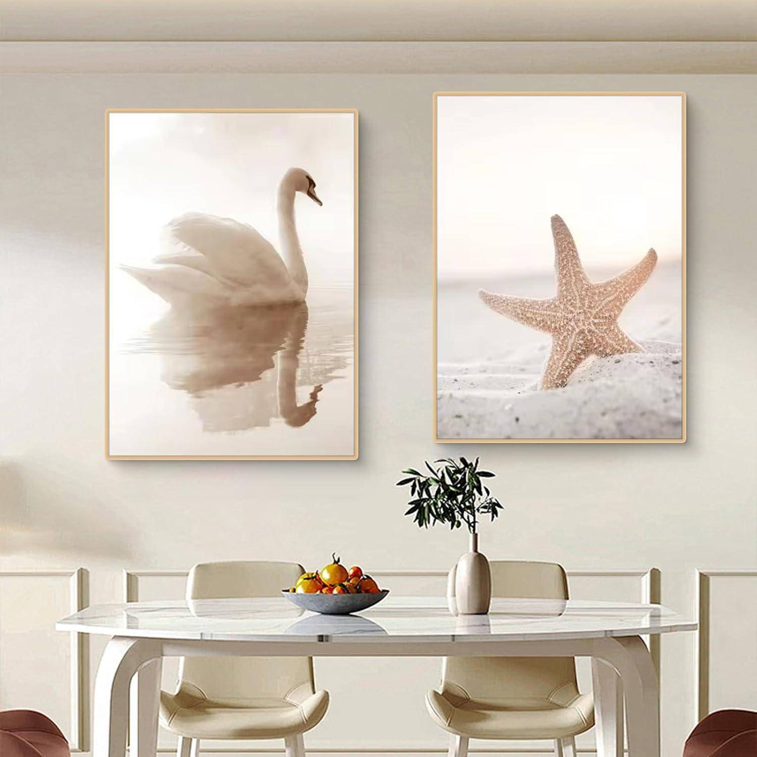 Ein moderner Essbereich mit einem weißen runden Tisch, zwei Stühlen und Wandkunst mit einem Schwan und einem Seestern darüber. Eine Obstschale und eine Pflanze schmücken den Tisch.