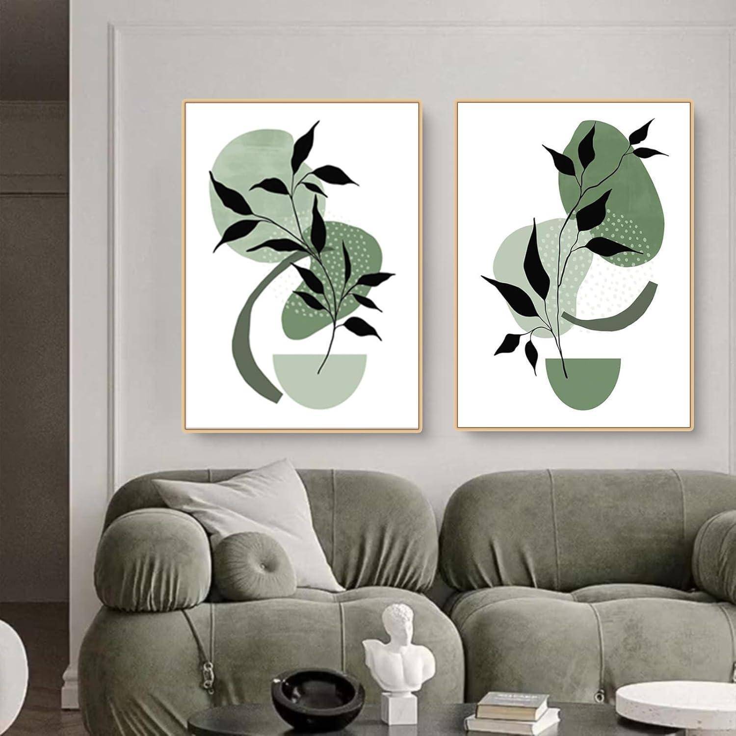 Ein Wohnzimmerausschnitt mit einem grünen Samtsofa vor einer weißen Wand, auf der zwei abstrakte botanische Kunstwerke hängen, die Formen und Blätter kunstvoll verschmelzen.