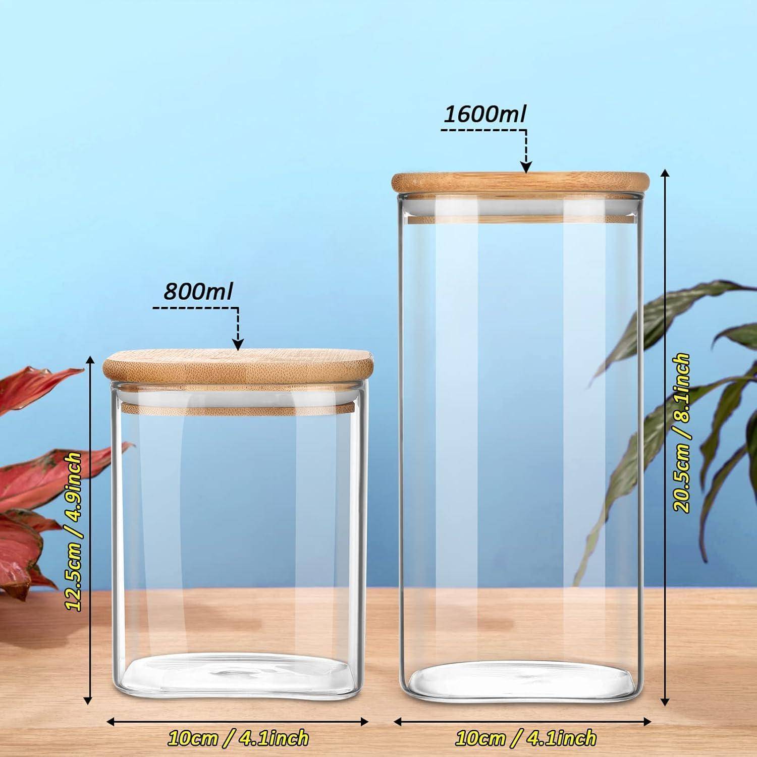 Zwei Glasgläser mit Holzdeckeln befinden sich auf einer Holzoberfläche vor einem blauen Hintergrund. Das linke Glas hat ein Volumen von 800 ml und ist 12,5 cm hoch, das rechte Glas hat ein Volumen von 1600 ml und ist 20,5 cm hoch.