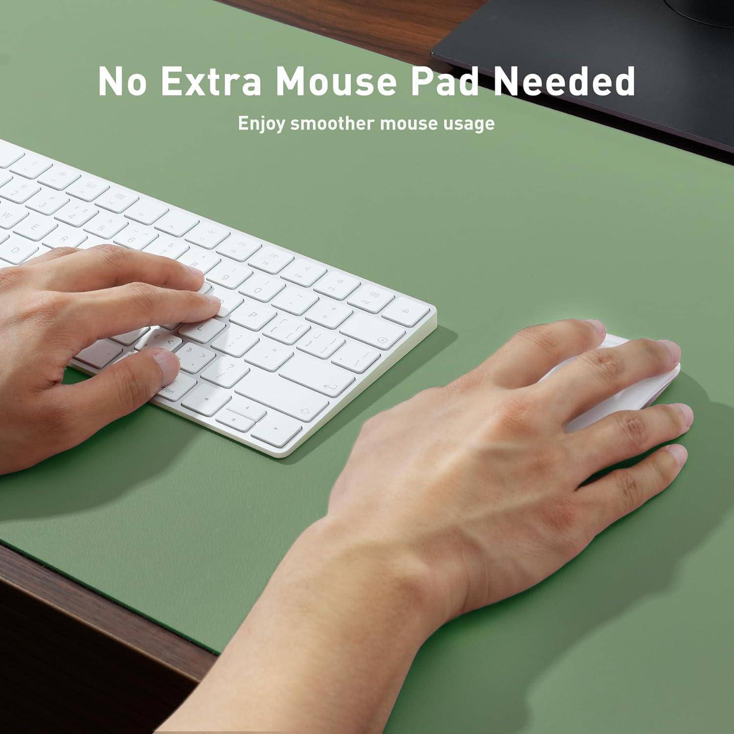 Hände, die eine weiße Maus und Tastatur auf einer grünen Schreibtischoberfläche bedienen. Text lautet: 'Kein zusätzliches Mousepad benötigt. Genießen Sie eine reibungslosere Mausbewegung.