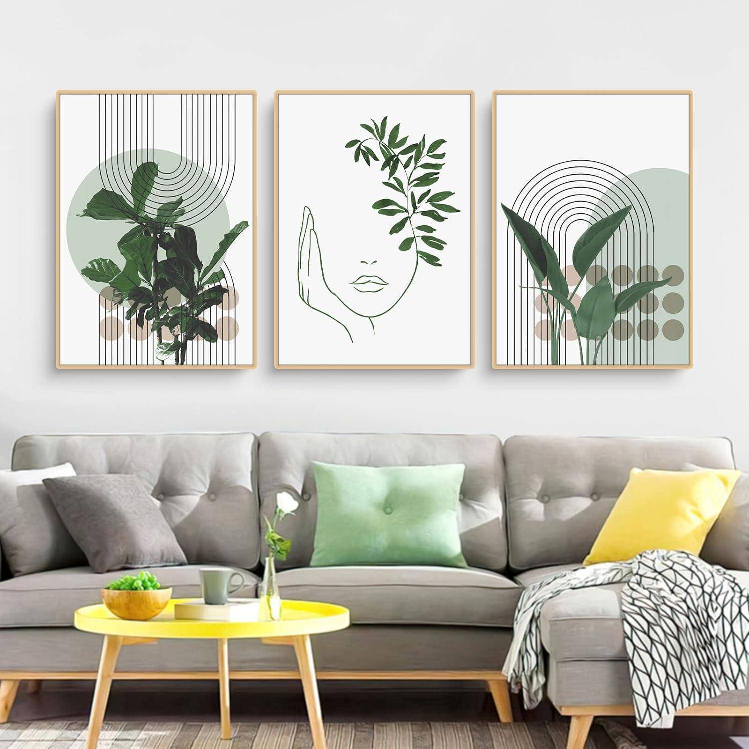 Ein moderner Wohnraum präsentiert ein graues Sofa mit grünen und gelben Kissen, einen Couchtisch mit Pflanzen und Büchern sowie abstrakte botanische Kunstwerke an der Wand.
