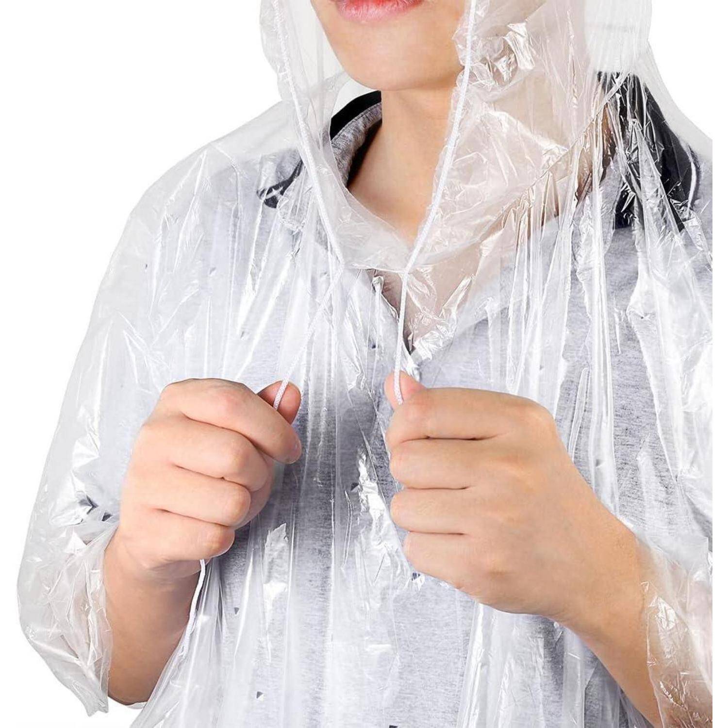 Eine Person, die einen durchsichtigen Plastik-Regenponcho trägt, von den Schultern aufwärts sichtbar, der die Kanten des Ponchos nahe am Hals festhält.