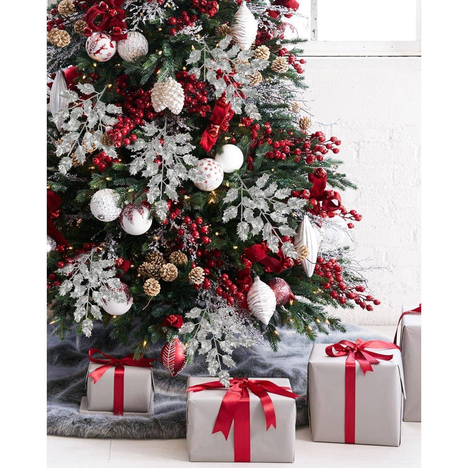 Ein geschmückter Weihnachtsbaum mit roten und silbernen Christbaumkugeln steht neben eingepackten Geschenken mit roten Schleifen.