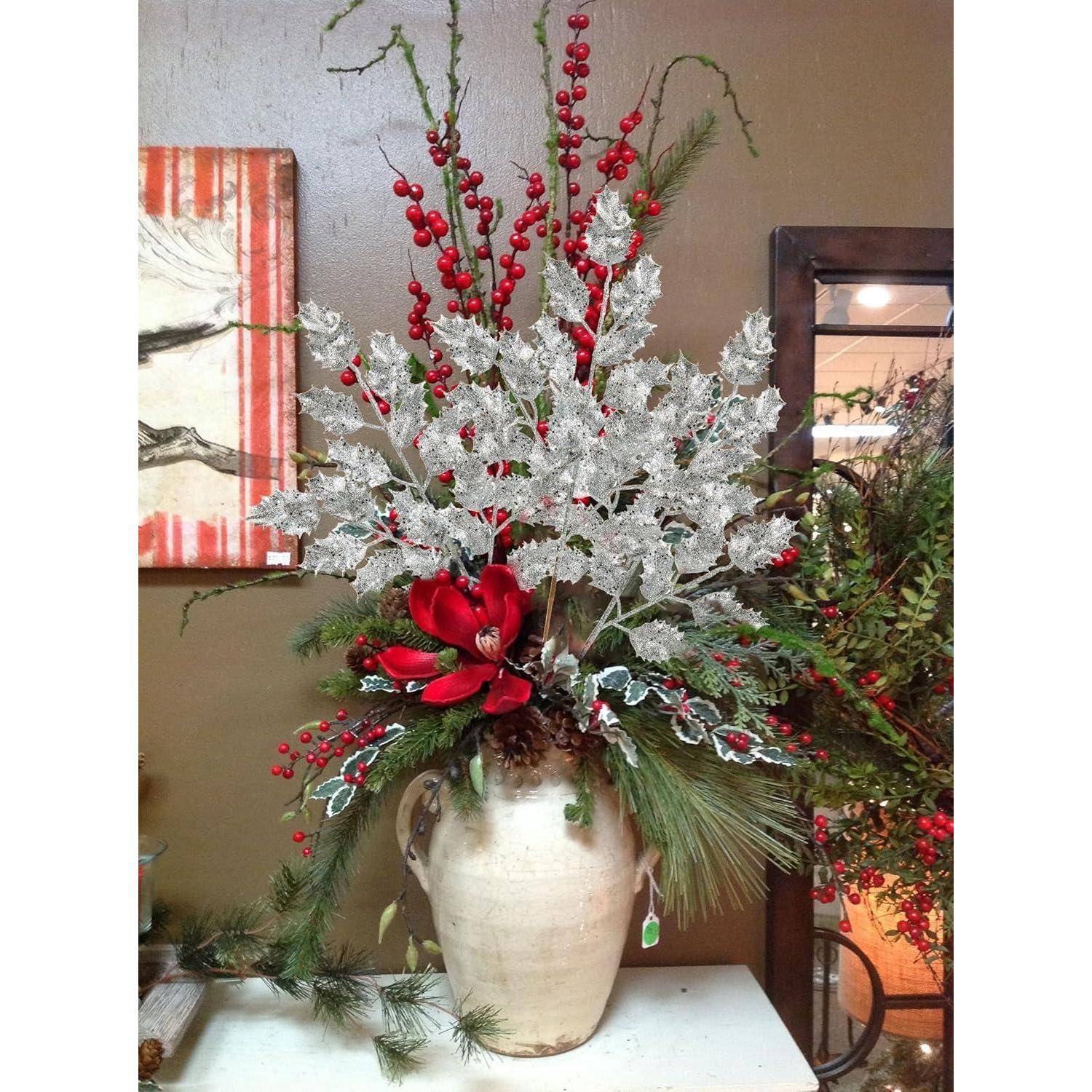 Eine große, dekorative Vase mit einer winterlichen Blumenkomposition, die rote Beeren, bereiftes Blattwerk, rote Blumen und Tannenzweige umfasst.