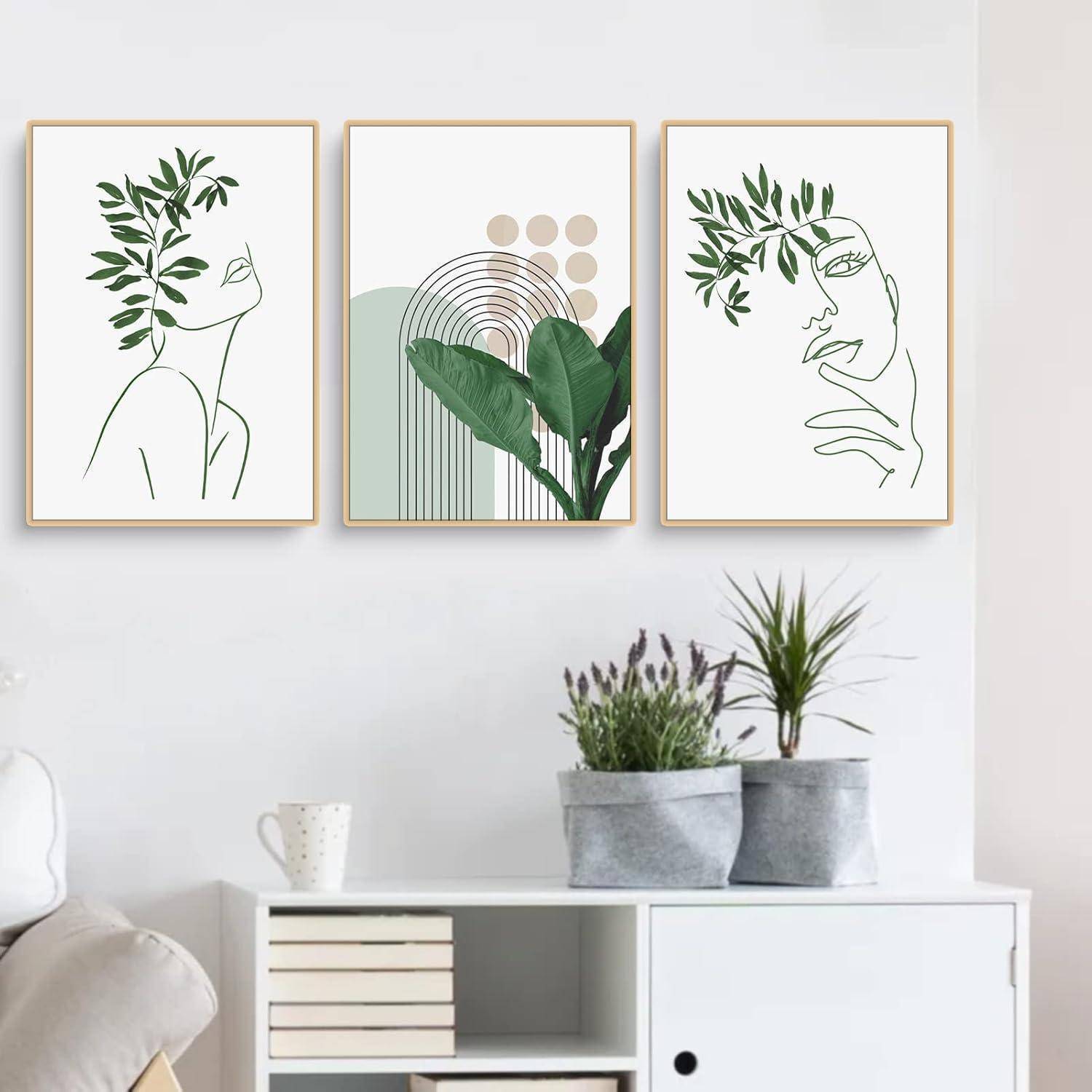 Drei minimalistische botanische Kunstdrucke an der Wand über einem modernen weißen Schrank, auf dem Zimmerpflanzen stehen.