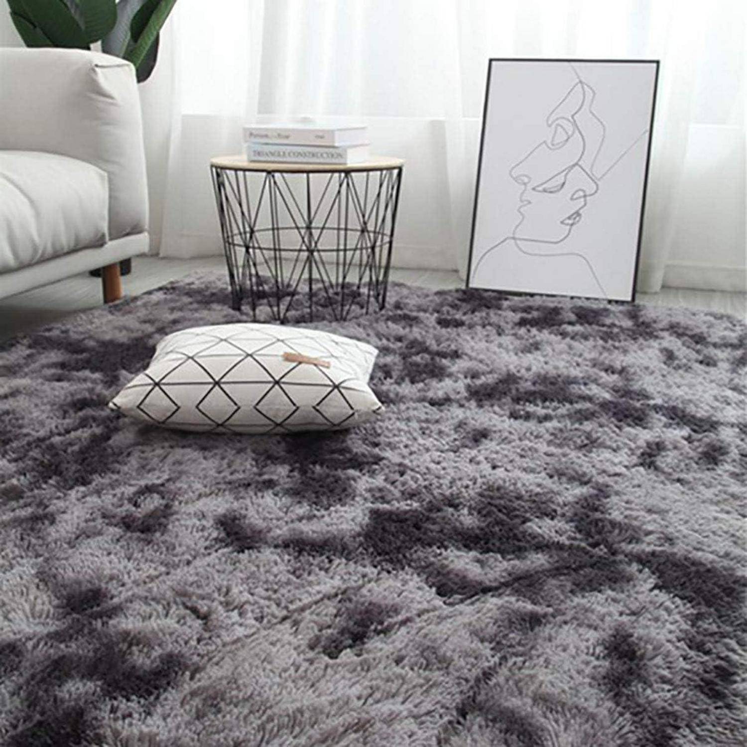 Ein modernes Wohnzimmer mit einem grauen Shaggy-Teppich, einem geometrisch gemusterten Kissen und minimalistischer Linienkunst auf dem Boden neben einem hellgrauen Sofa.