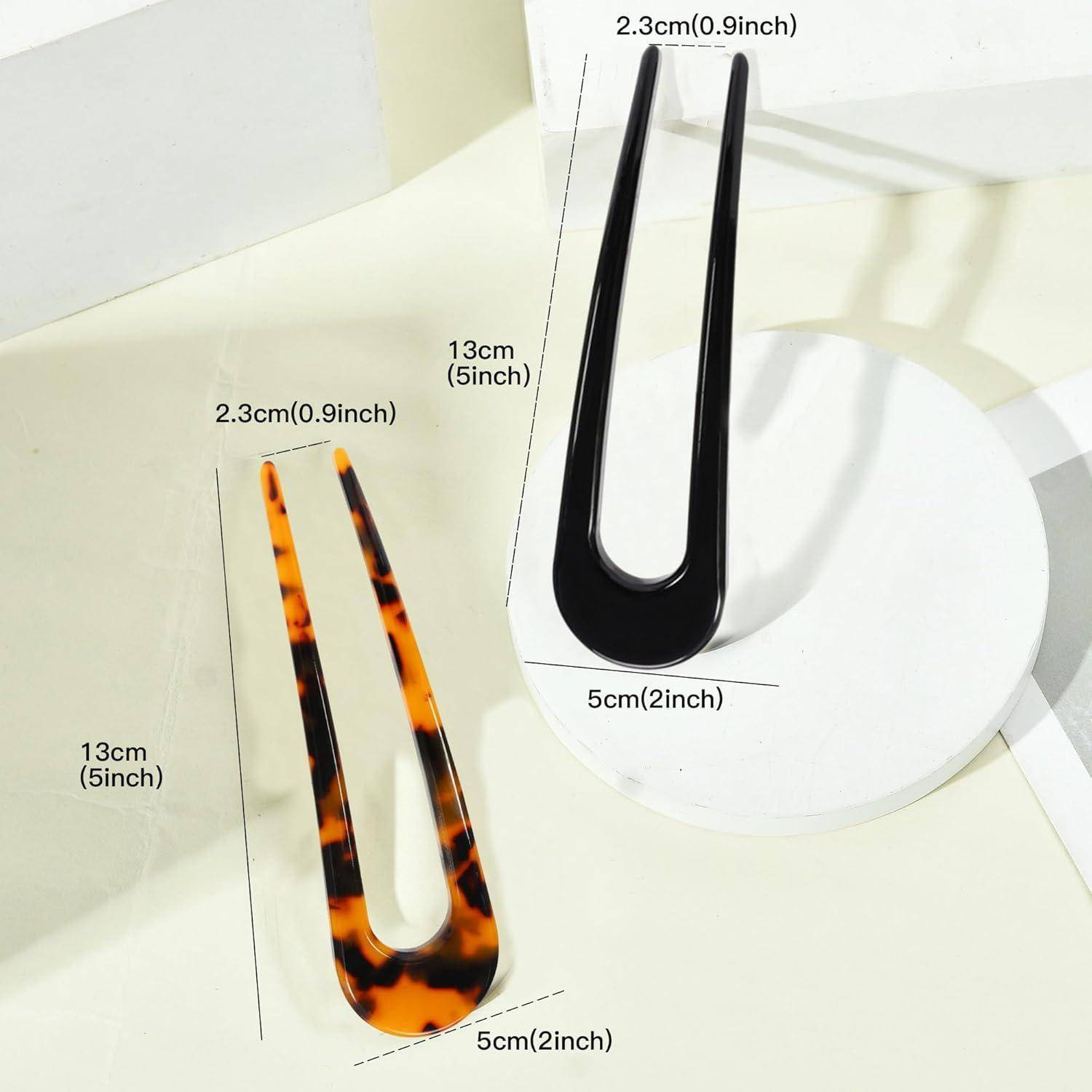 Schildpatt-Haarnadel, 13 cm lang und 2,3 cm breit, und schwarze Haarnadel, 13 cm lang und 5 cm breit, auf einer weißen Oberfläche präsentiert.