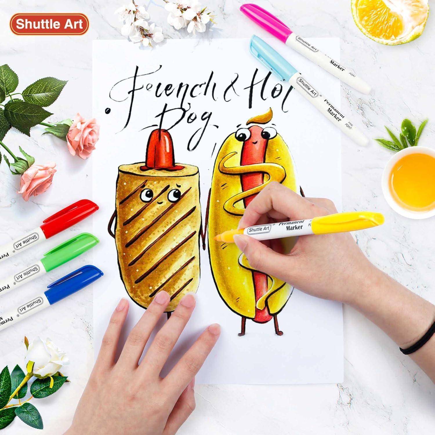 Eine Person malt eine verspielte Zeichnung eines Hotdogs, der in französisch inspirierter Kleidung gekleidet ist. Verschiedenfarbige Marker und kleine Blumen umgeben das Papier.