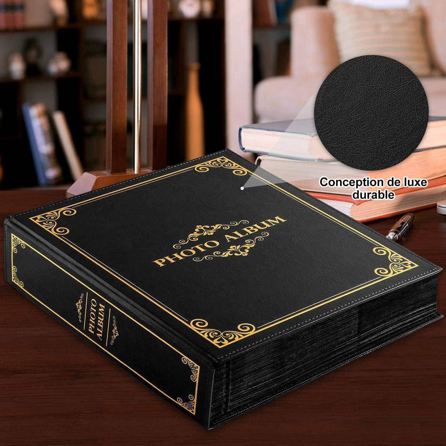 Ein schwarzes Fotoalbum mit aufwendigen Goldverzierungen liegt auf einem Holztisch. Ein Detailausschnitt zeigt das strukturierte Material des Albums, mit dem Text ‚Conception de luxe durable'. Bücher befinden sich im Hintergrund.
