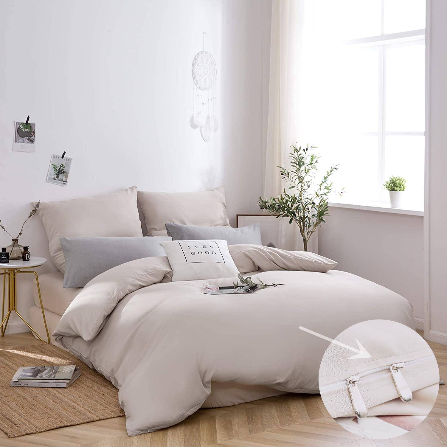 Ein gemütliches Schlafzimmer mit einer beigen Bettdecke, zwei grauen Kissen und einem Kissen mit der Aufschrift ‚Good Vibes'. Die Dekoration umfasst Fotos, einen Traumfänger und eine kleine Pflanze.