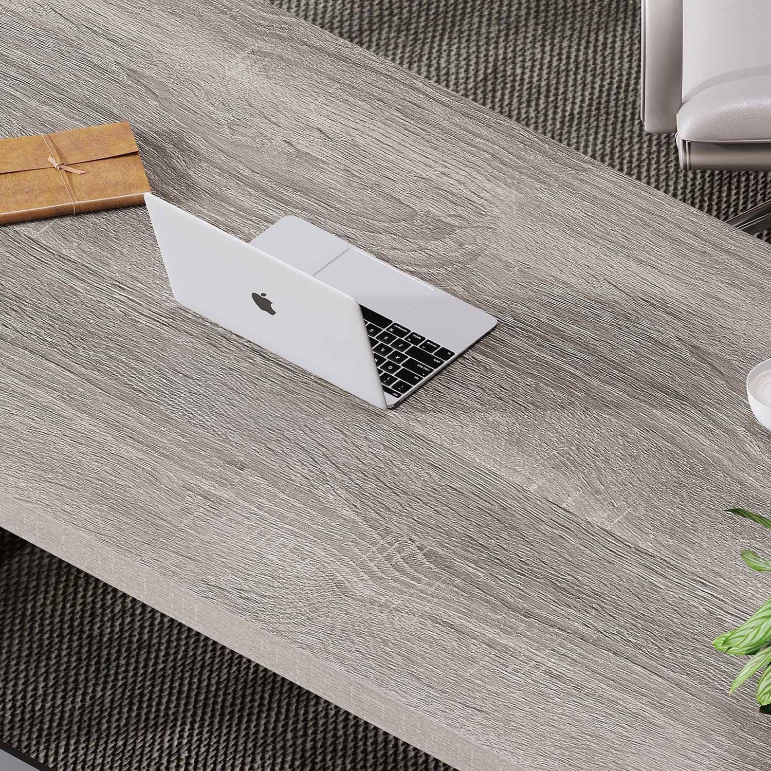 Ein silberner Laptop mit einem Apple-Logo steht auf einem Holztisch neben einem braunen Notizbuch und deutet auf eine Arbeitsplatzumgebung hin.