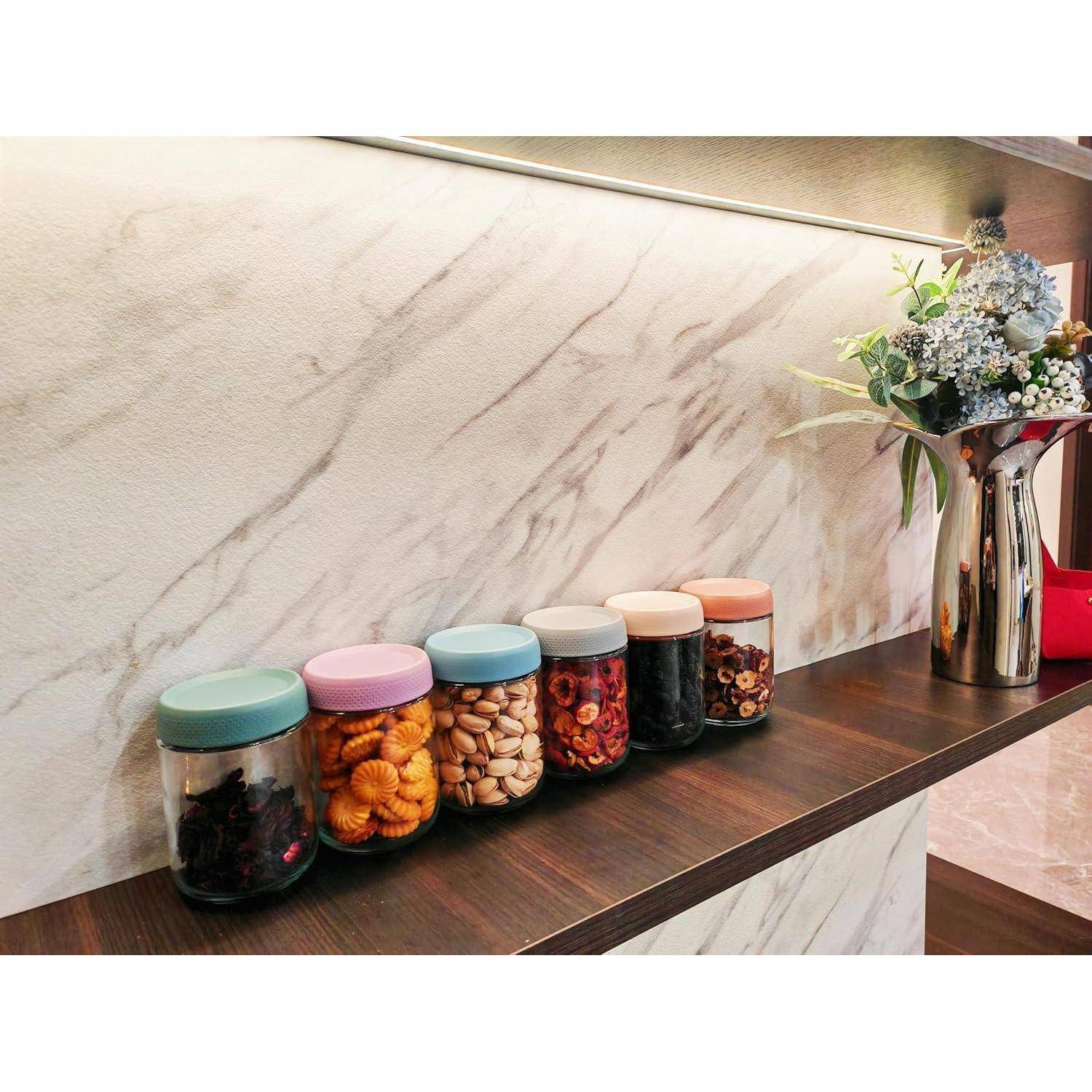 Gläser gefüllt mit Snacks und Nüssen säumen ein Holzregal, neben einer metallischen Vase mit blauen und weißen Blumen, unter warmem Licht.
