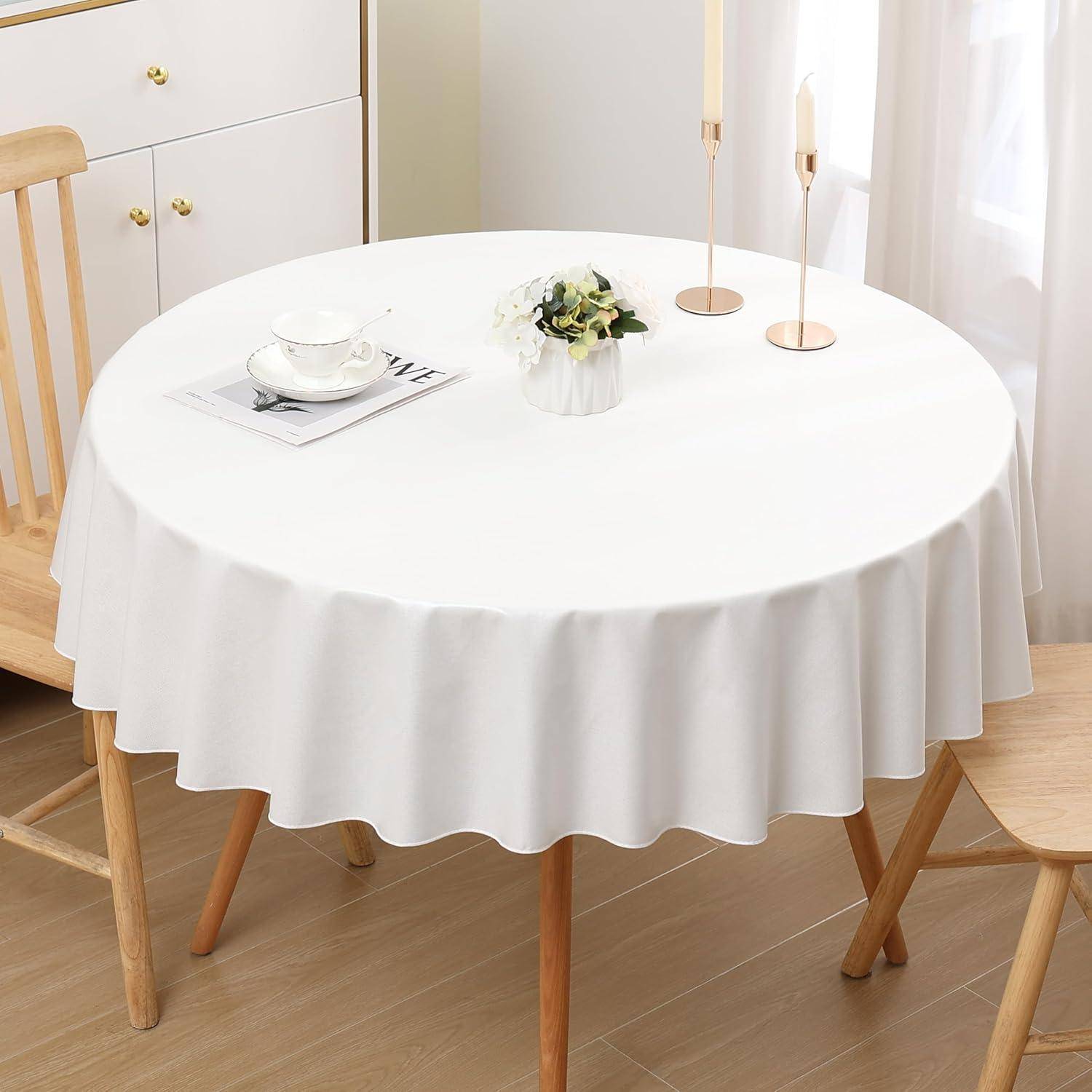 Ein runder Esstisch, bedeckt mit einer weißen Tischdecke, gedeckt mit einer Teetasse, Untertasse, einer kleinen Vase mit Blumen und zwei hohen Kerzenständern.