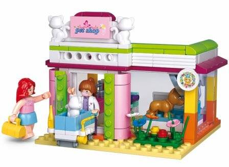 Spielbaukasten mit einem farbenfrohen Tiergeschäft, vor dem eine Figur steht, ein Hund und Blumen zu sehen sind. Ein Schild über dem Eingang trägt die Aufschrift ‚Tiergeschäft'.