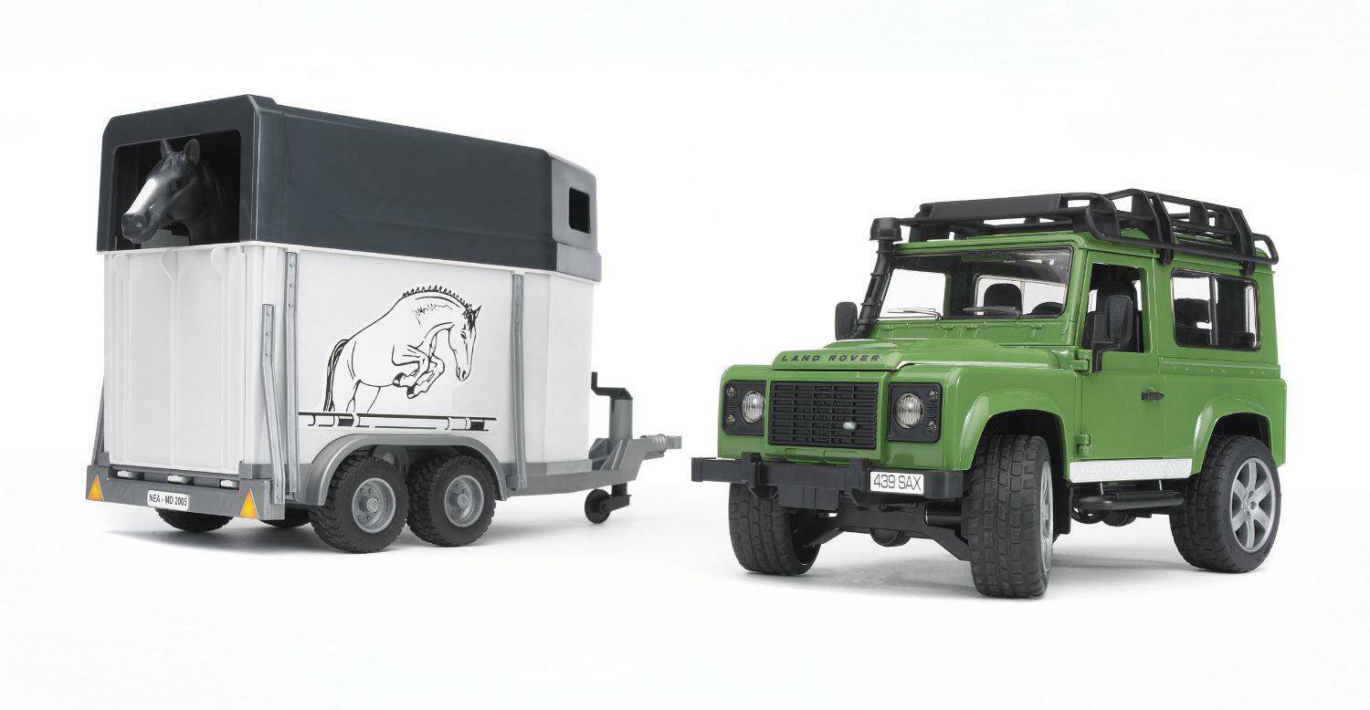Grüner Land Rover Defender, der einen Pferdeanhänger mit einer Pferdezeichnung an seiner Seite zieht.
