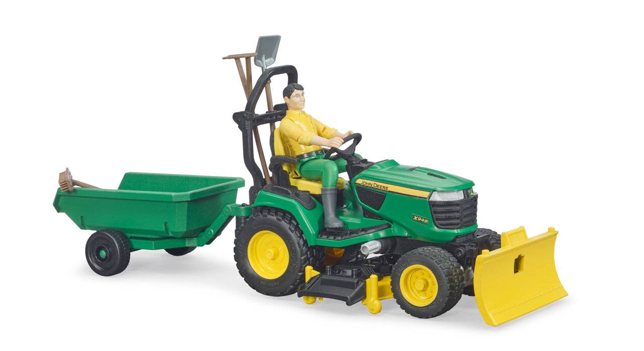 Ein Spielzeugtraktor mit gelben Rädern, grünem Körper und einer kleinen Figur auf dem Sitz. Angehängt ist ein grüner Anhänger mit Gartengeräten.