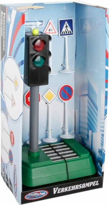 Eine Spielzeug-Ampel mit roten, gelben und grünen Lichtern steht auf einem Modell-Zebrastreifen, wobei im Hintergrund Schilder verschiedener Formen sichtbar sind.