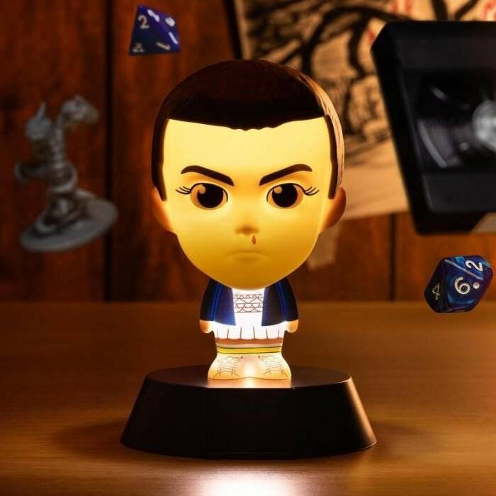 Eine kleine Lampe in Form einer stilisierten Person mit einer leuchtenden Basis. Verschiedene Würfel und ein Schachfigur schweben im Hintergrund.