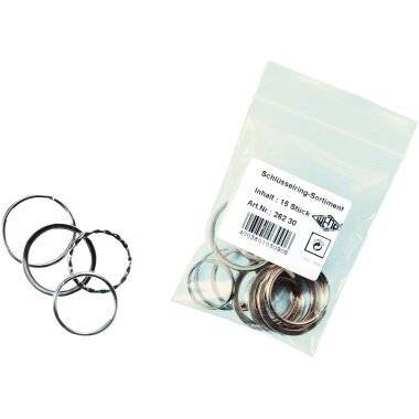 Ein durchsichtiger Plastikbeutel, beschriftet mit 'Schlüsselring-Sortiment Inhalt: 15 Stück', der Metallschlüsselringe enthält, neben mehreren losen Schlüsselringen.