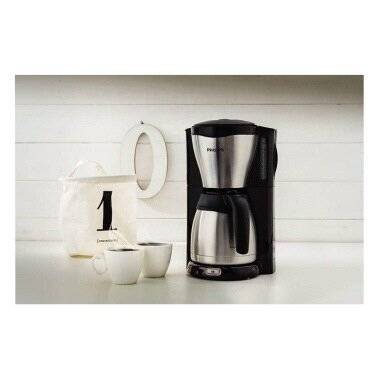 Ein silberner und schwarzer Kaffeemaschine steht auf einer weißen Arbeitsplatte neben zwei weißen Tassen und einem weißen Behälter mit der Nummer '1'.