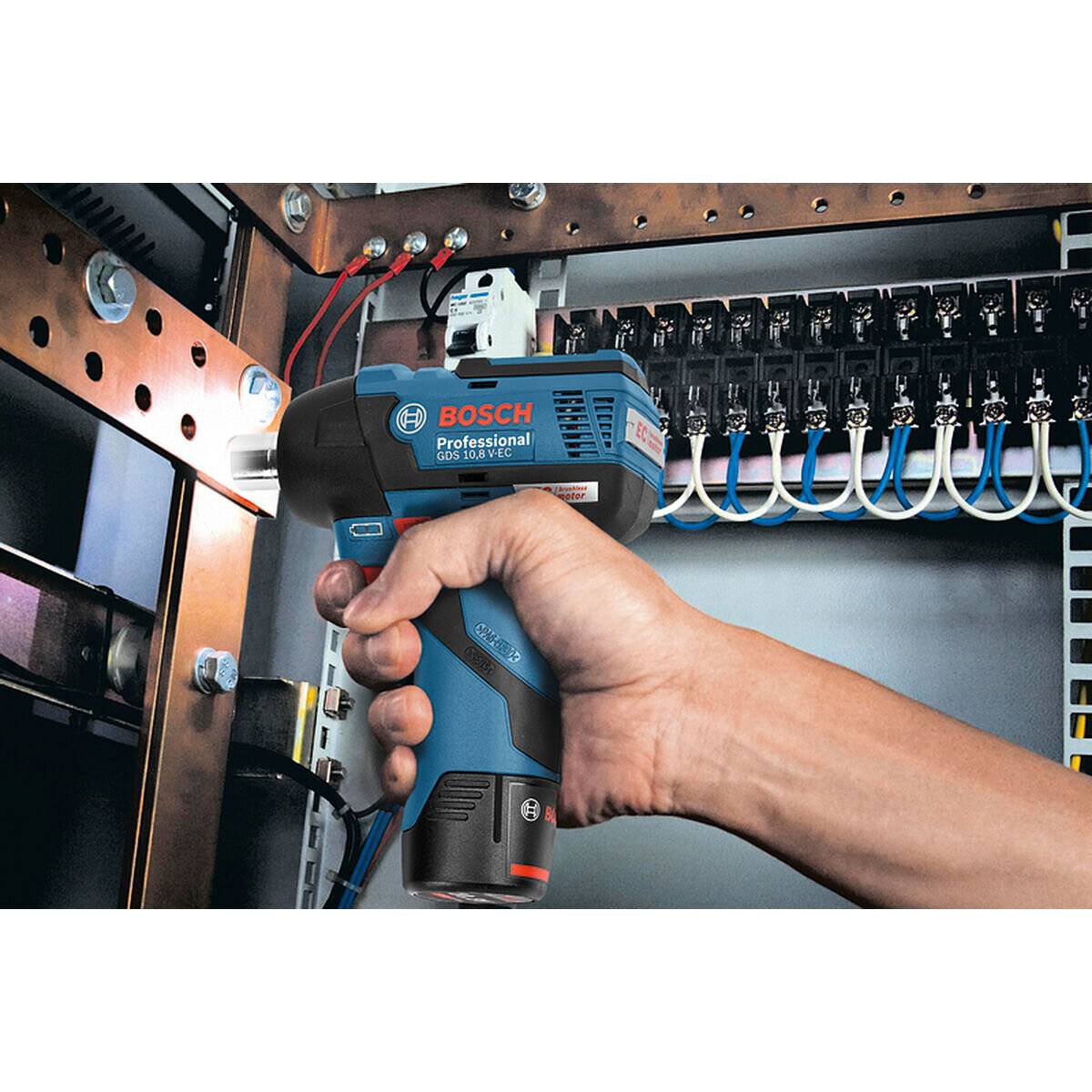 Eine Person verwendet ein Bosch-Elektrowerkzeug, um die Verkabelung in einer elektrischen Verteilerdose zu justieren. Das Werkzeug beleuchtet den Arbeitsbereich und unterstützt so die Präzision.