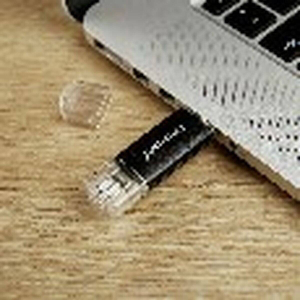 Ein USB-Stick, der teilweise in den USB-Anschluss eines Laptops auf einer Holzoberfläche gesteckt ist.