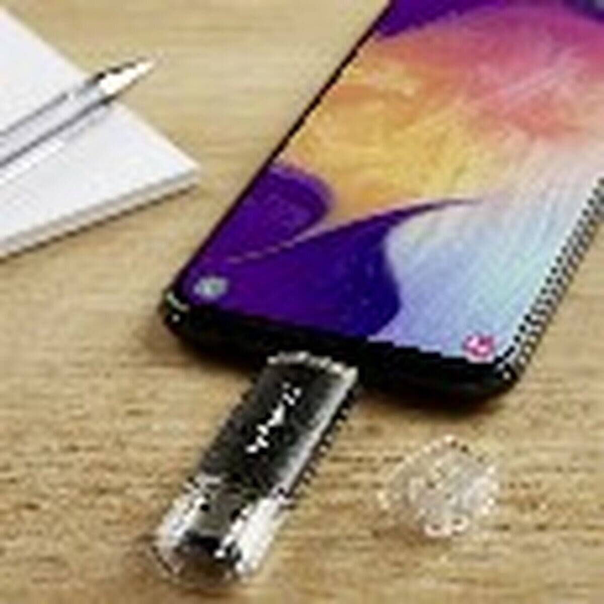 Ein Smartphone mit einem bunten Bildschirm ist mit einem USB-Stick verbunden. Ein Stift liegt in der Nähe auf einem Holztisch.