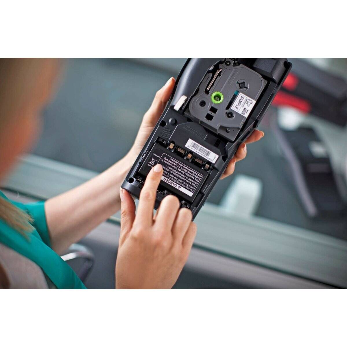 Eine Person, die ein Gerät bedient und dessen offenes Batteriefach zeigt. Der Fokus liegt auf dem Einsetzen oder Überprüfen der Batterien des Geräts.