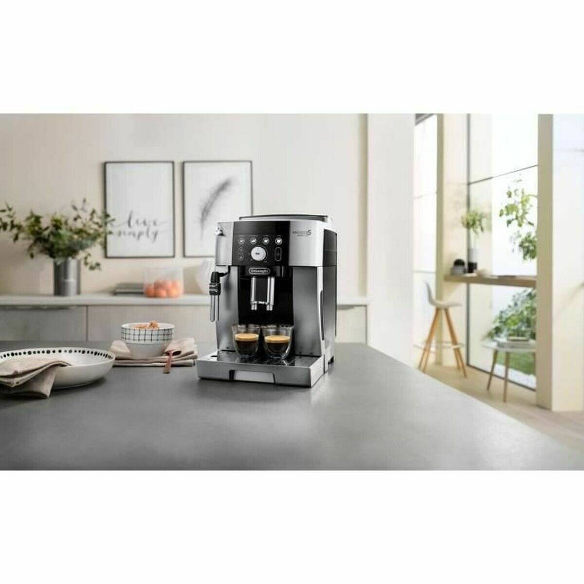 Eine moderne Espressomaschine auf einer Küchenarbeitsplatte, die zwei Tassen Kaffee brüht. Sonnendurchfluteter Essbereich mit minimalistischer Einrichtung im Hintergrund.