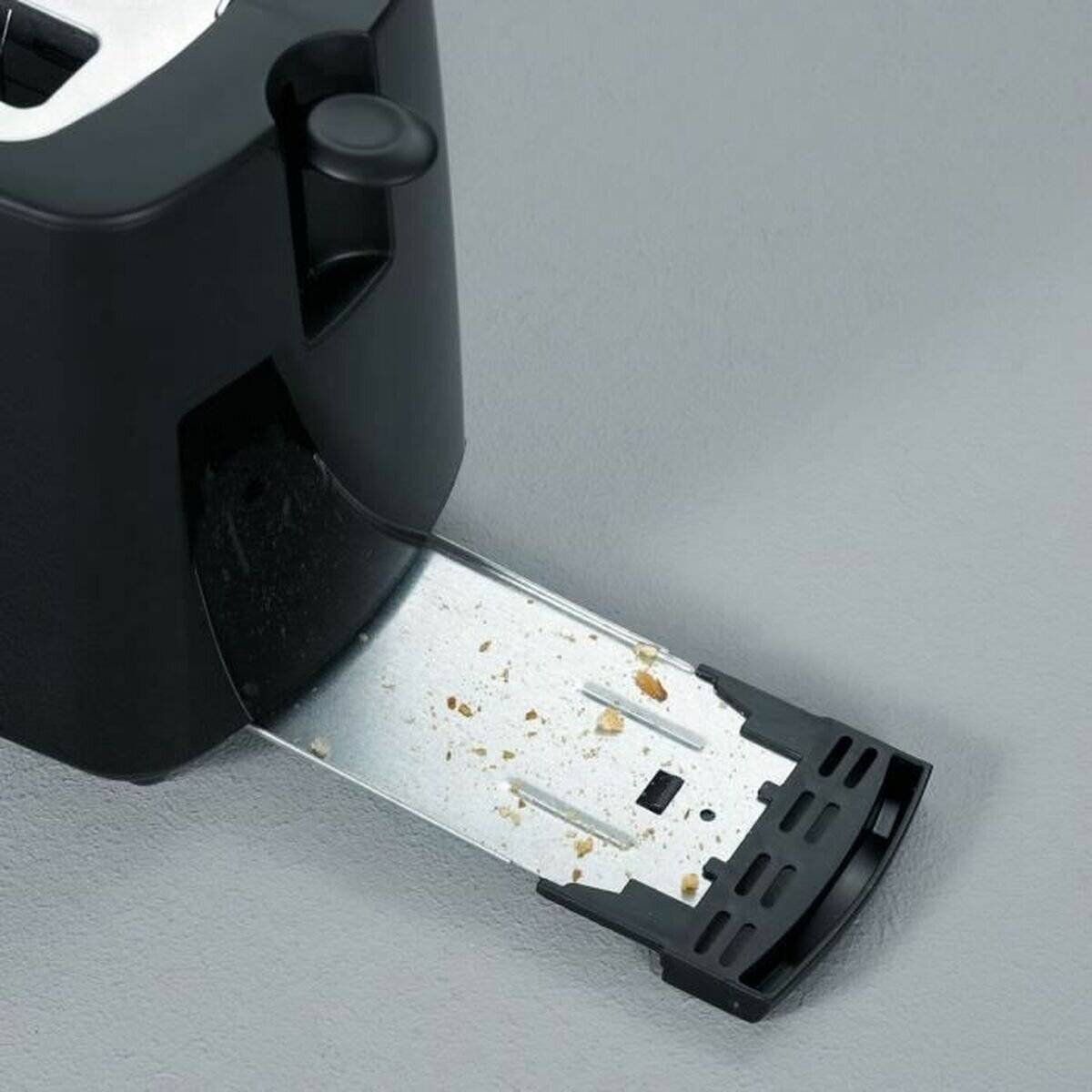 Ein Toaster mit herausgezogenem Krümelblech, auf dem verstreute Brotkrümel liegen und eine einfache Reinigungsfunktion veranschaulichen.