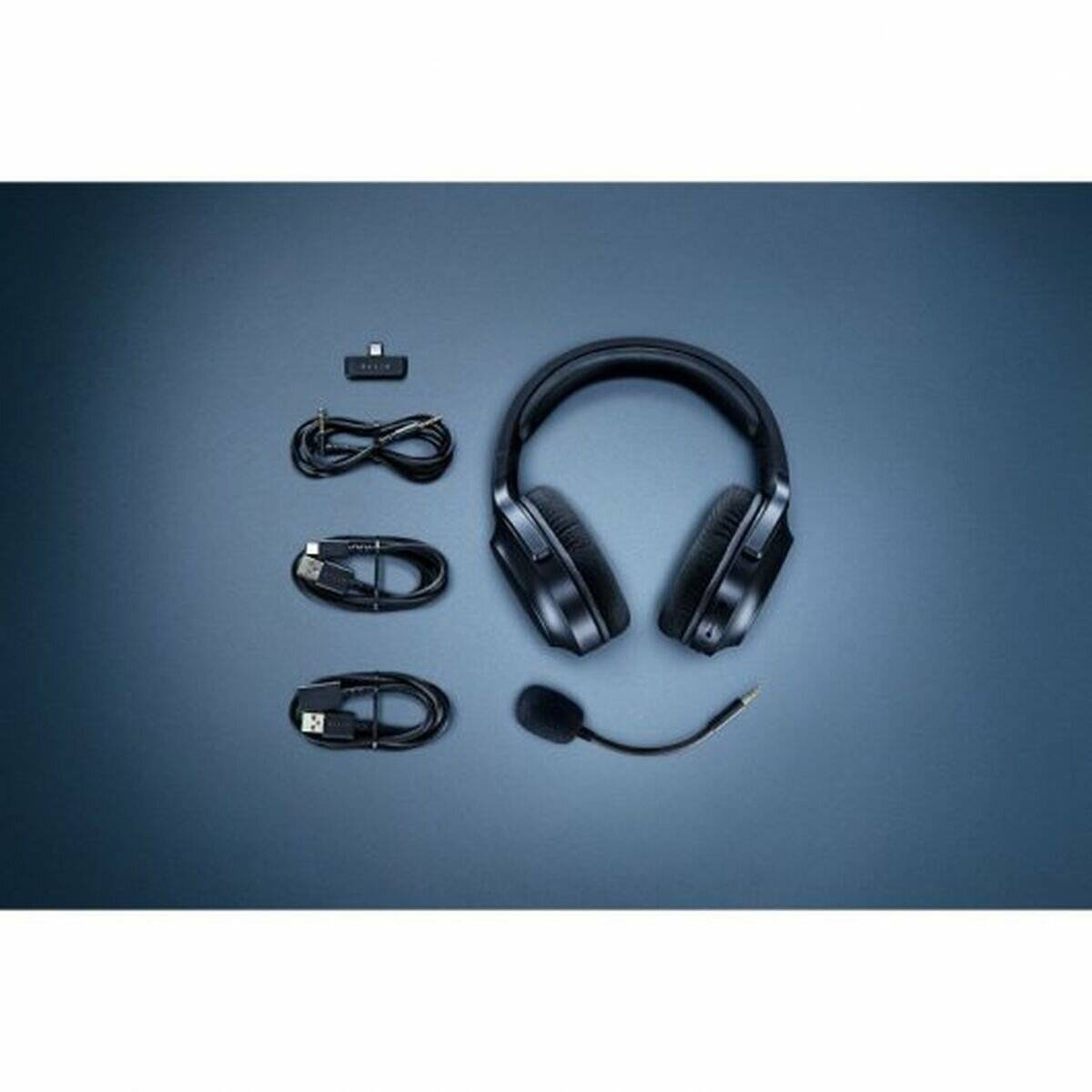 Ein schwarzes Headset mit Mikrofon, USB-Adapter und zwei Verbindungskabeln, die ordentlich auf einem blauen Hintergrund ausgelegt sind.