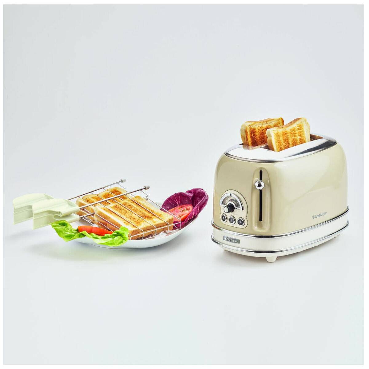 Ein beiger Toaster mit herausspringenden Toastscheiben, daneben ein Toasthalter gefüllt mit gegrillten Toasts und bunter Garnitur auf einer eleganten Oberfläche.
