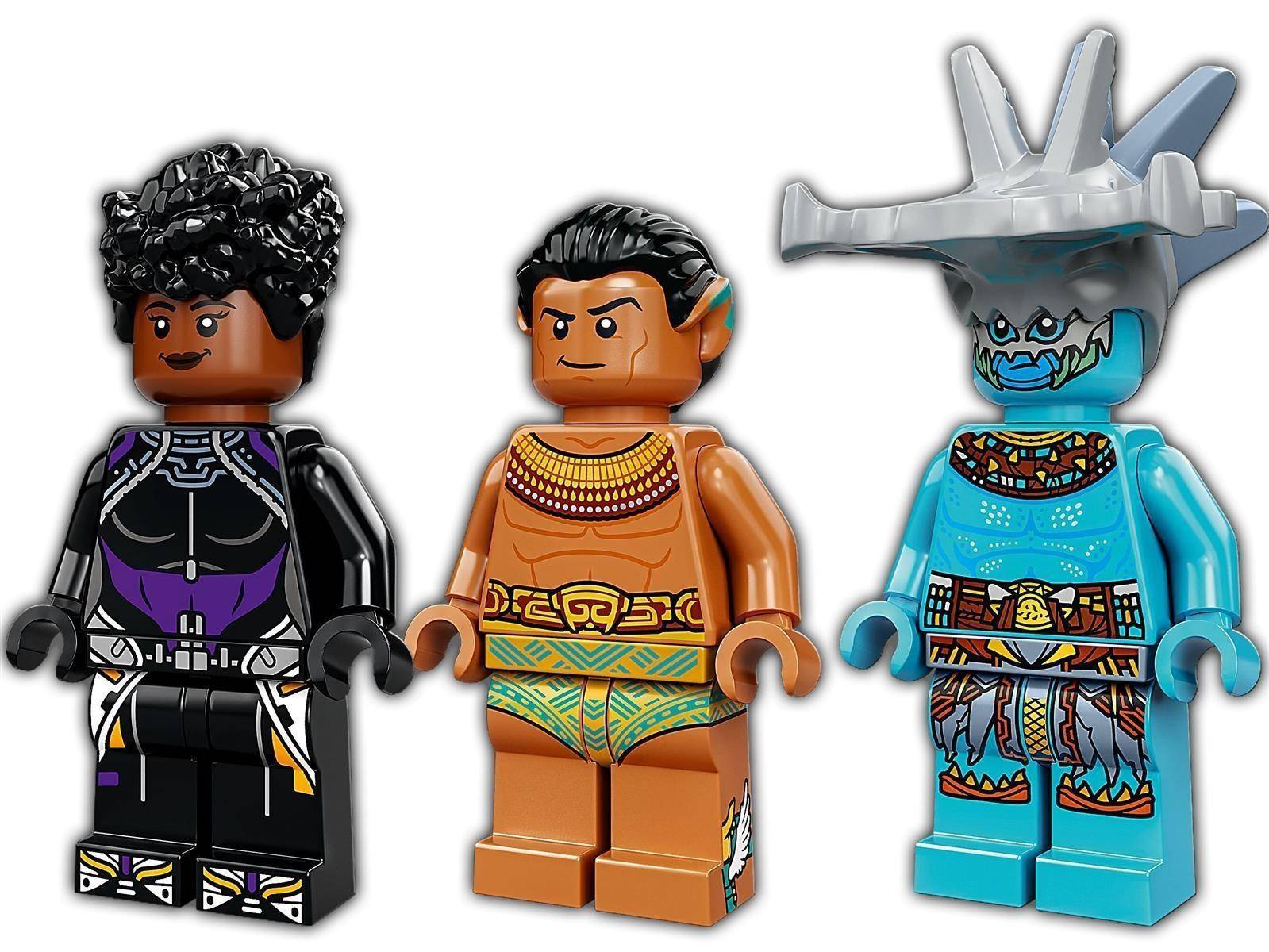 Drei LEGO-Minifiguren aus Black Panther: eine schwarz gekleidete Figur, eine beige Figur mit goldenem Schmuck und ein blauer Meereskrieger mit silbernem Helm.