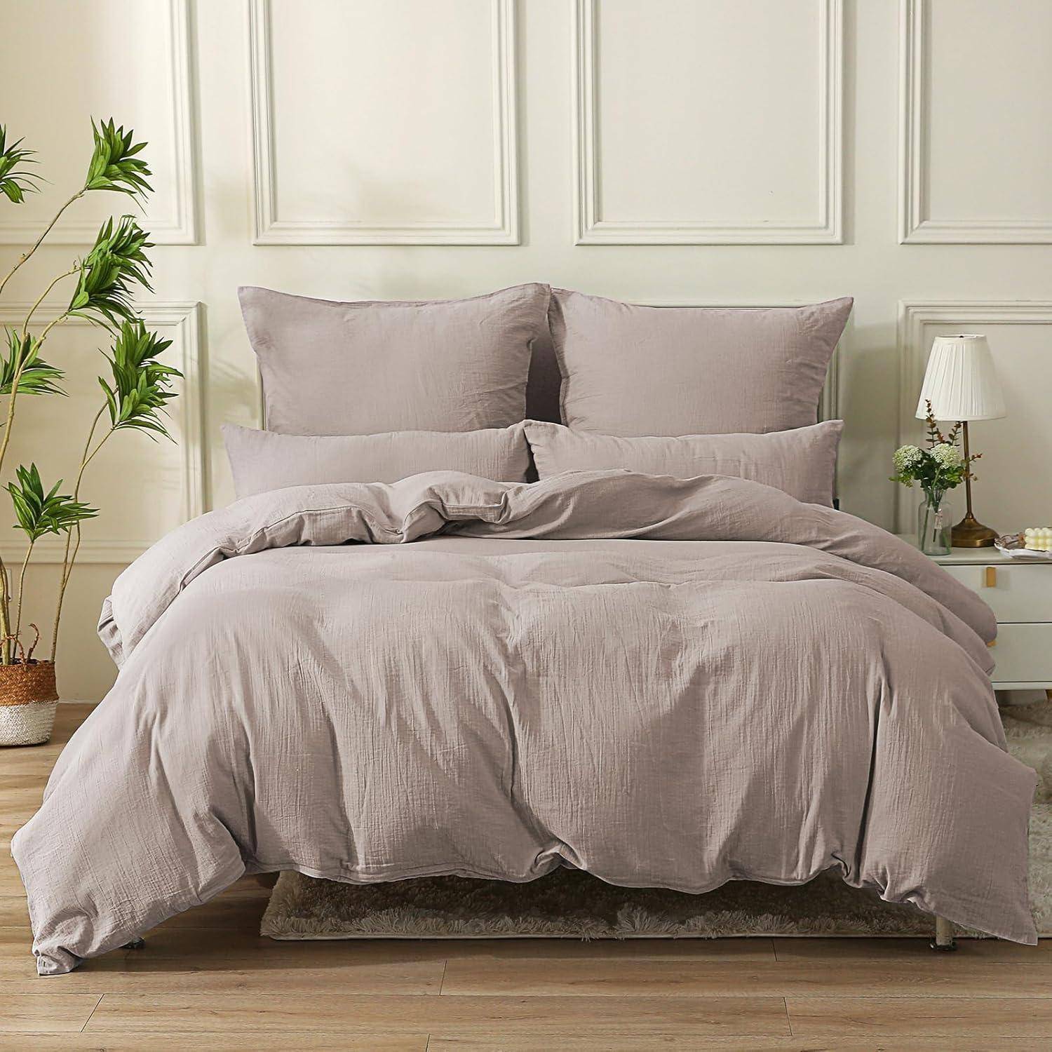 Ein ordentlich gemachtes Bett mit grauen Kissen und einer Bettdecke, platziert in einem Raum mit weißen Vertäfelungswänden, einem kleinen Nachttisch und einer Topfpflanze.